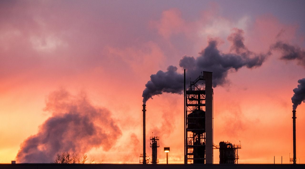 Refinery towers and chimneys against a red evening sky